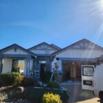 Exterior painting preparation on a blue-gray home with a covered garage area