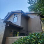 Exterior painting in progress on brown two-story siding and trim