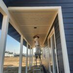 Professional painter coating covered patio beams and ceiling