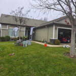 Painting crew and equipment outside a gray residential home