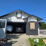 Freshly painted gray two-story home exterior with white trim and black garage door