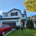 Freshly painted white two-story home with black shutters and red garage door